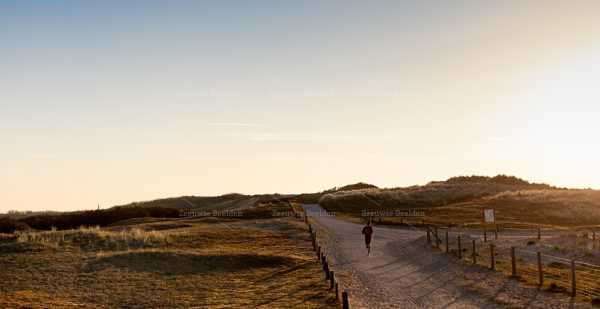 Avondlicht met hardloper in duinen