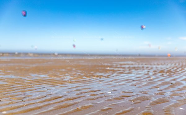 Close-up nat zand met kitesurfers