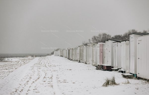 Rij met strandhuisjes in de sneeuw