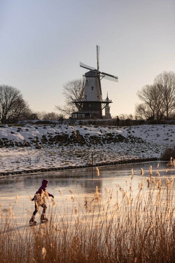 Eenzame schaatser naast molen De Koe